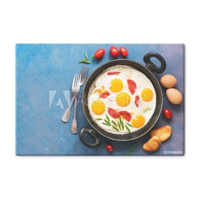 sniadanie-smazone-jajka-z-pomidorami-podawane-na-patelni-na-niebieskim-tle-widok-z-gory-miejsce-na-tekst